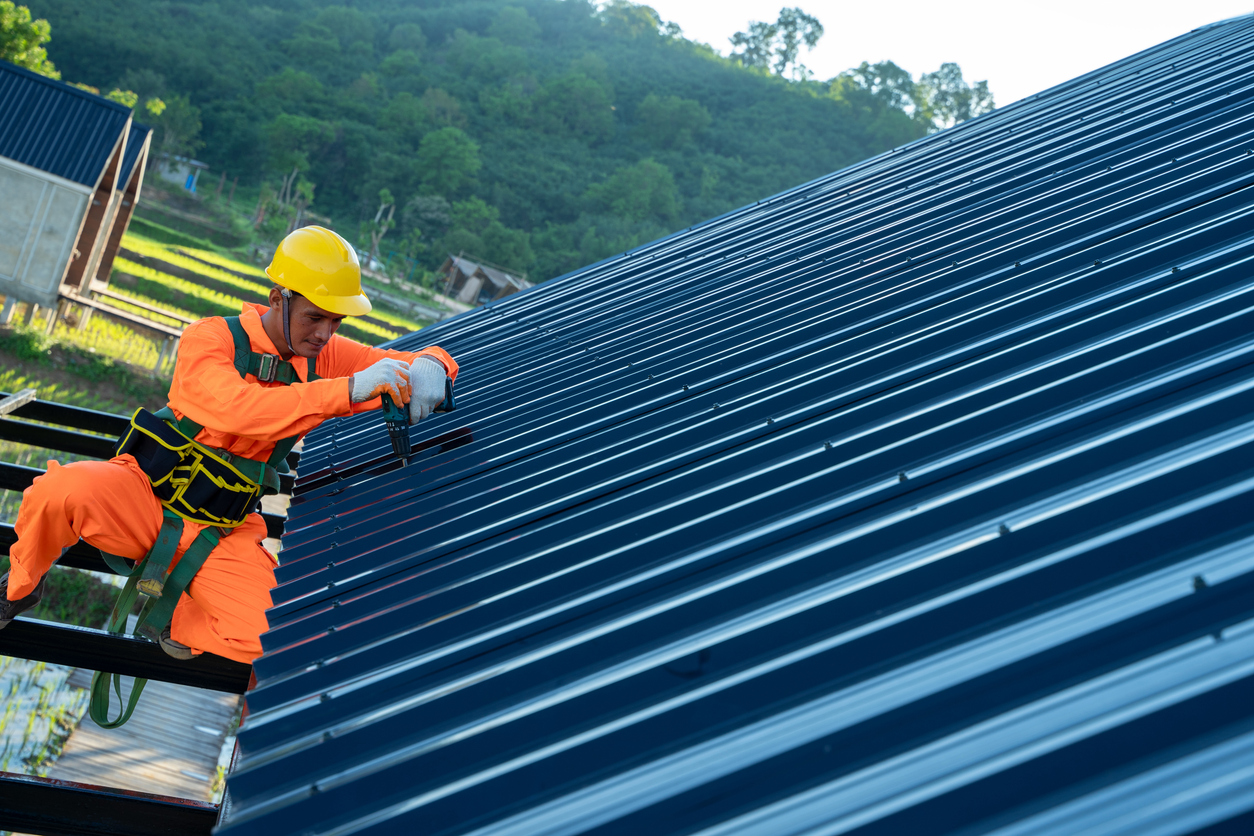 Roofer worker use electric drill installing new roofs.